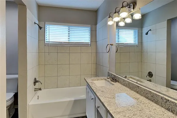a bathroom with a granite countertop sink a toilet and bathtub