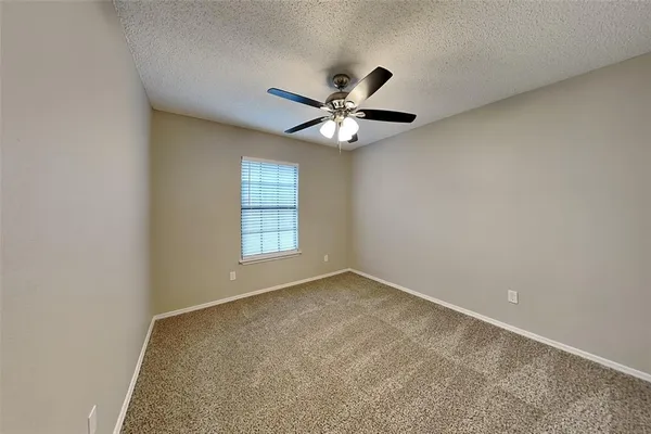 an empty room with windows and ceiling fan