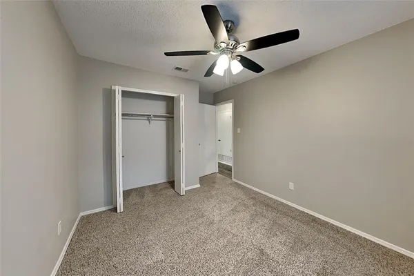 an empty room with closet and a chandelier fan