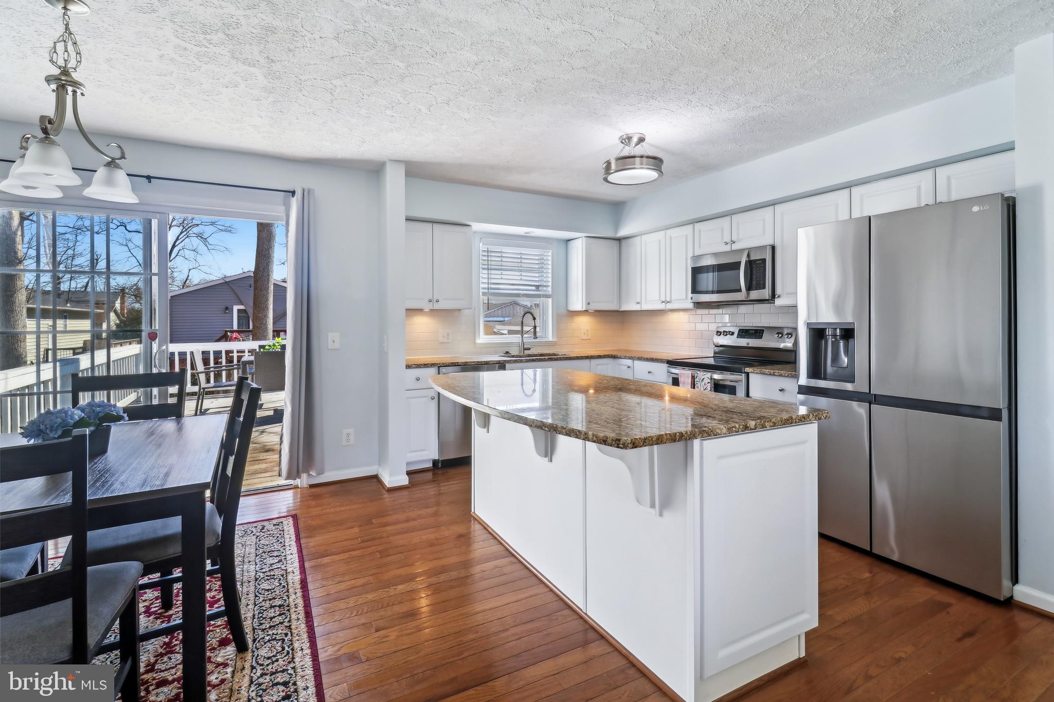 1809 Keymar Road Edgewater, MD 21037 - Photo 7 of 49 a kitchen with stainless steel appliances granite countertop a stove a sink dishwasher a refrigerator and a dining table with wooden floor