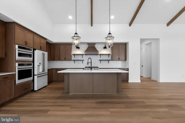 a large kitchen with stainless steel appliances a large counter top a stove and a refrigerator