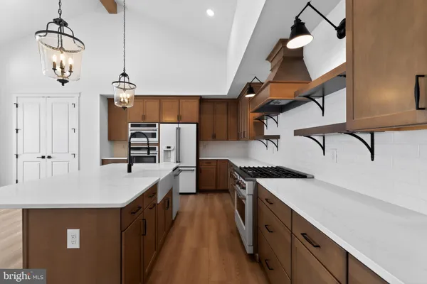 a kitchen with stainless steel appliances granite countertop a sink a stove and a wooden floors