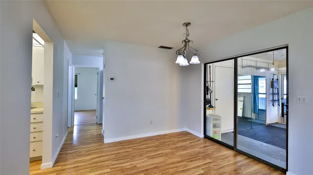 a view of a hallway with wooden floor and a chandelier