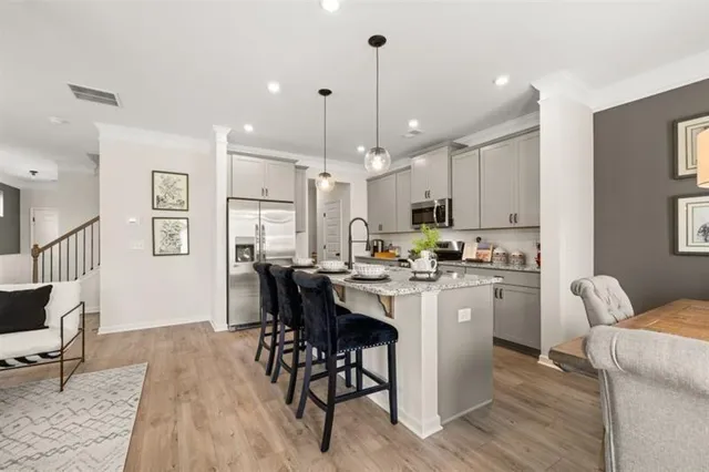 a kitchen with stainless steel appliances kitchen island granite countertop a dining table chairs stove and white cabinets