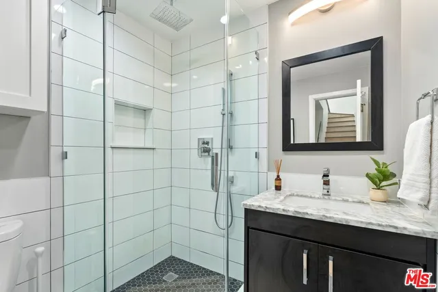 a bathroom with a granite countertop sink a mirror and shower