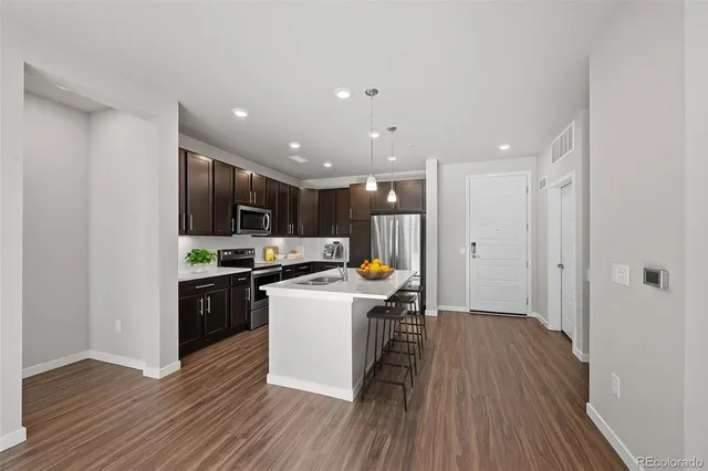 a kitchen that has a lot of cabinets a sink and wooden floor