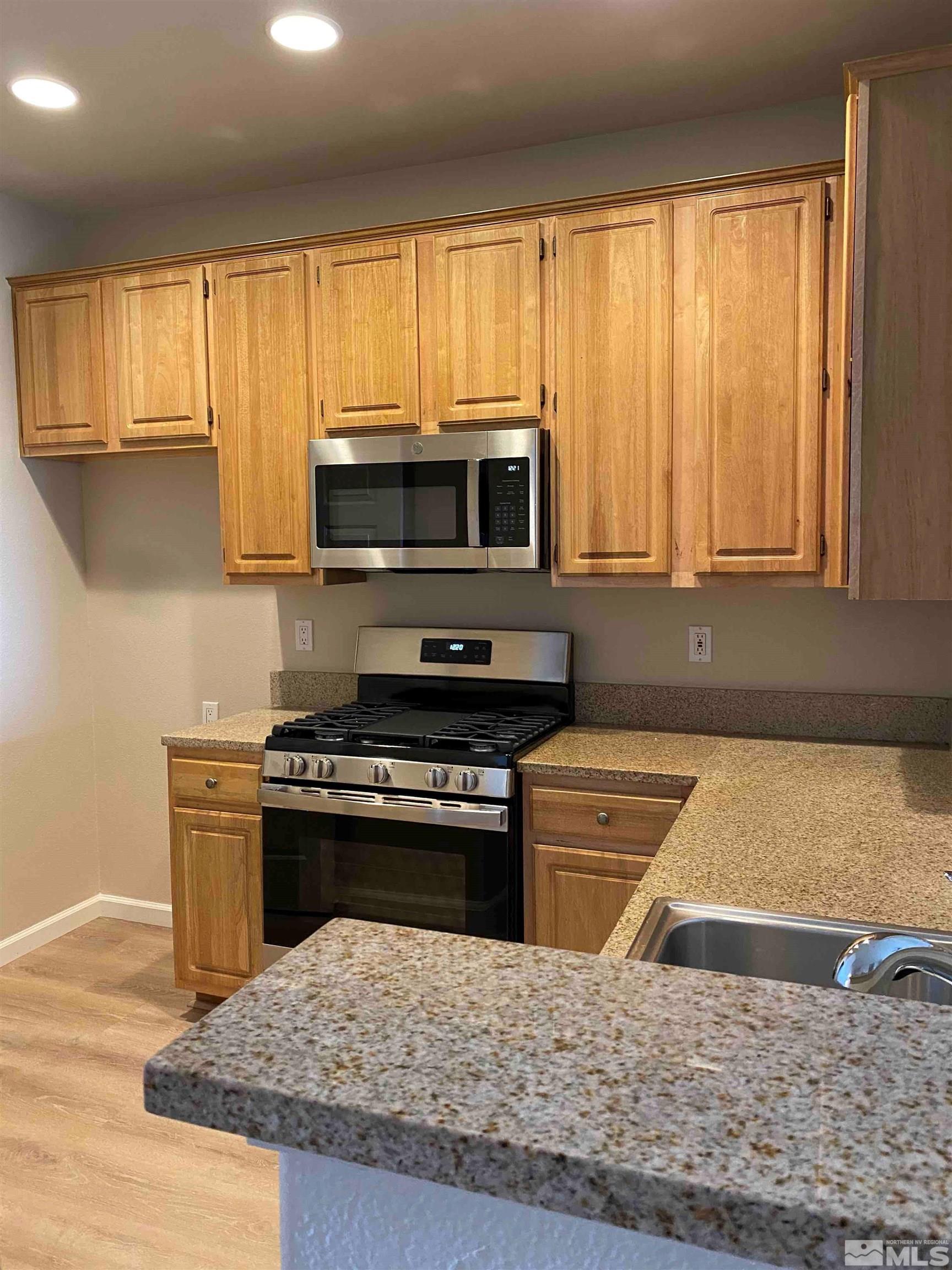 900 S Meadows, Unit 3722 Reno, NV 89521 - Photo 4 of 26 a kitchen with a stove a microwave and wooden cabinets
