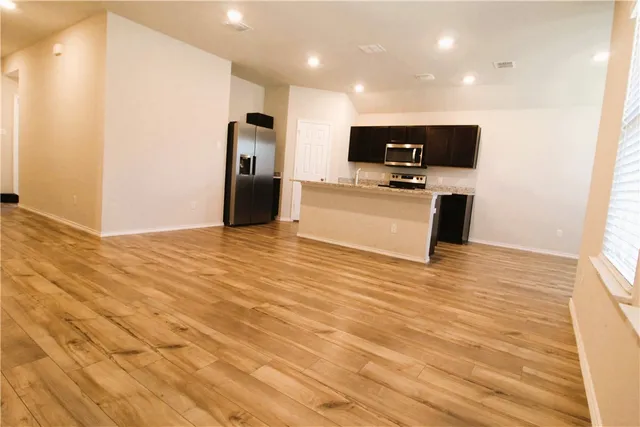 a view of kitchen with stainless steel appliances granite countertop a refrigerator and a stove top oven