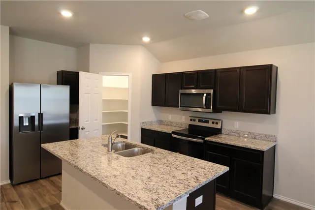 a kitchen with stainless steel appliances kitchen island granite countertop a refrigerator and a stove top oven