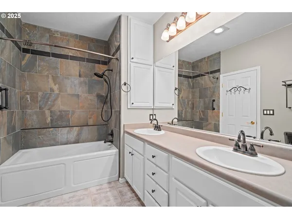 a bathroom with a double vanity sink a large mirror and bathtub