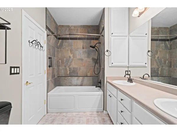 a bathroom with a tub sink vanity granite and shower