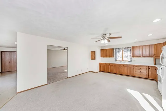 a view of an empty room with window and a kitchen