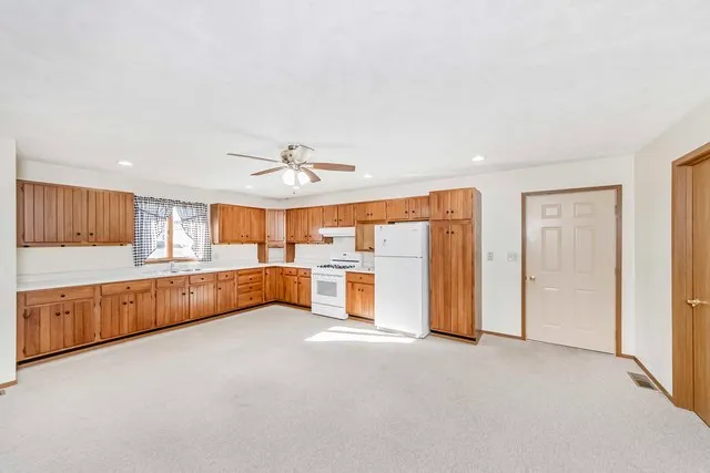 an empty room with chandelier fan and windows