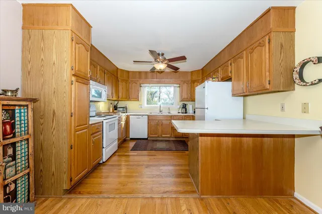 a large white kitchen with stainless steel appliances granite countertop a stove a sink and a refrigerator