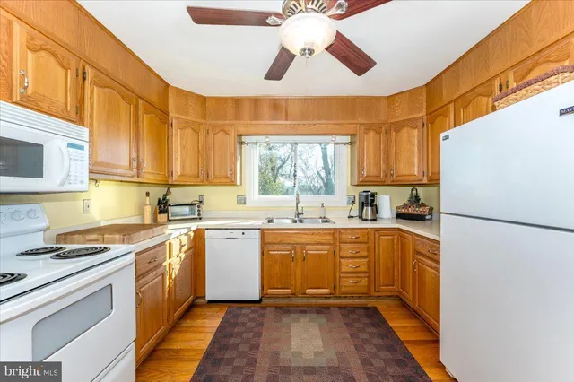 a kitchen with a stove top oven a sink dishwasher and a refrigerator with wooden floor