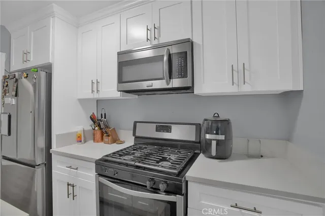 a kitchen with stainless steel appliances granite countertop white cabinets and a stove a refrigerator with white cabinets