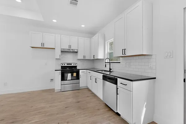 a kitchen with granite countertop white cabinets and stainless steel appliances