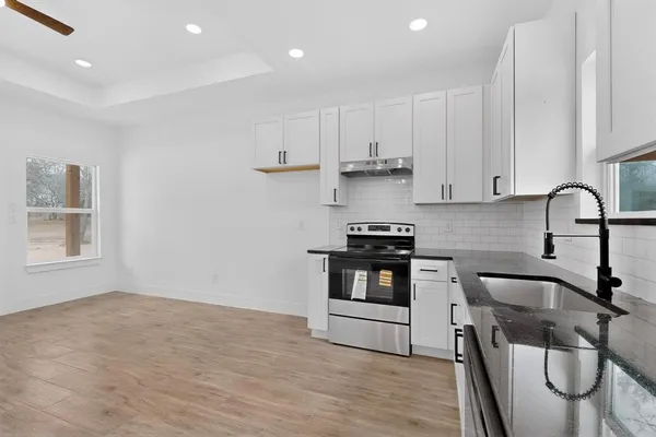 a kitchen with granite countertop a stove a sink and a microwave