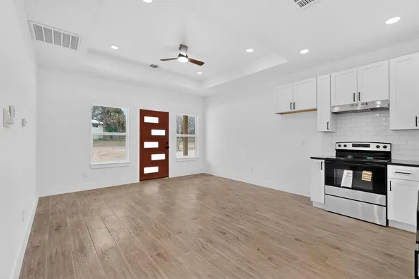 a view of an empty room with window and wooden floor