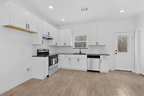 a kitchen with stainless steel appliances white cabinets a sink a stove a refrigerator and cabinets