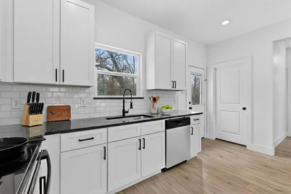 a kitchen with stainless steel appliances granite countertop a sink and cabinets with wooden floor