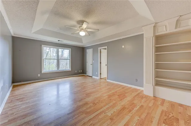 a view of an empty room with a window and wooden floor