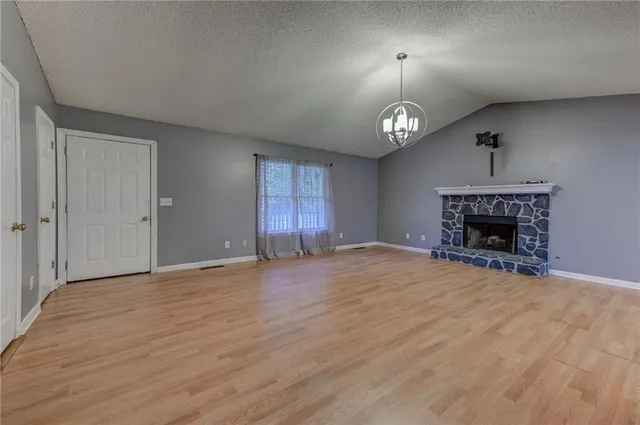 an empty room with fireplace cabinet and windows