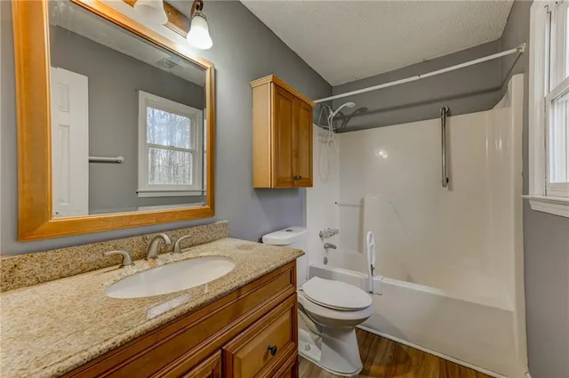 a bathroom with a granite countertop sink toilet and shower