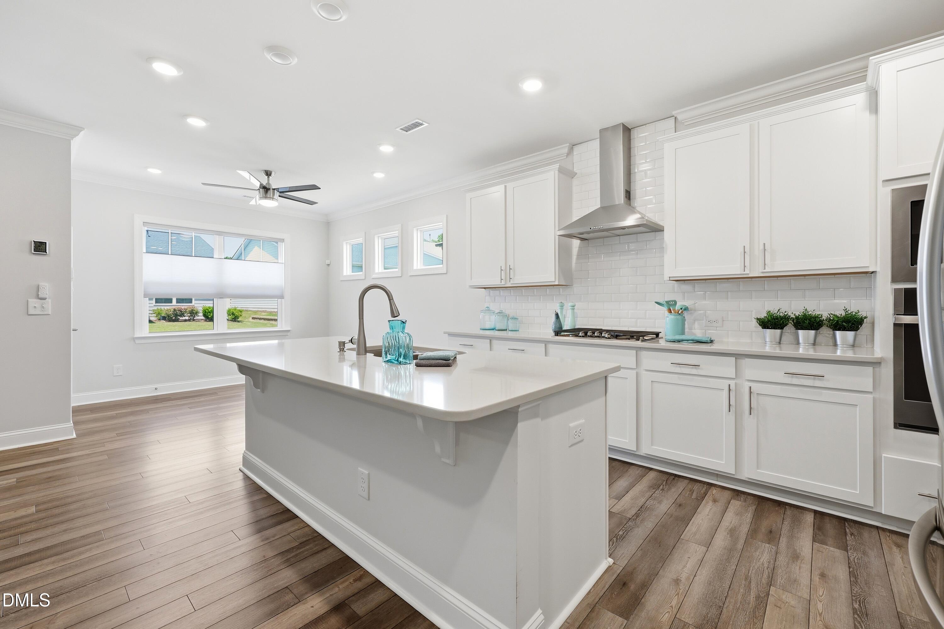 289 English Violet Lane Raleigh, NC 27610 - Photo 11 of 40 a kitchen with stainless steel appliances granite countertop a sink a stove a refrigerator and white cabinets with wooden floor