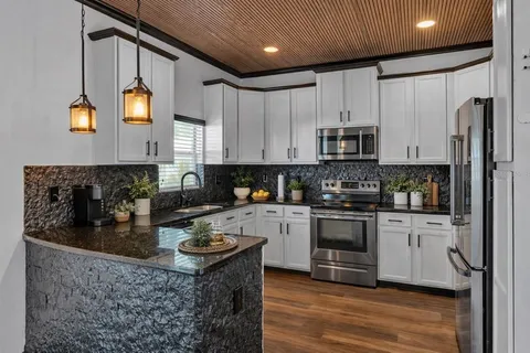 a kitchen with stainless steel appliances granite countertop a refrigerator a stove and a sink