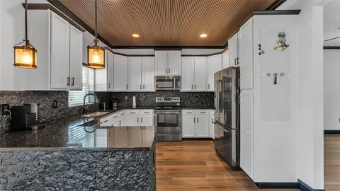 a large kitchen with stainless steel appliances granite countertop a stove a refrigerator a oven a dining table and chairs with wooden floor