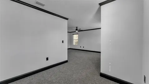an empty room with a window and a ceiling fan