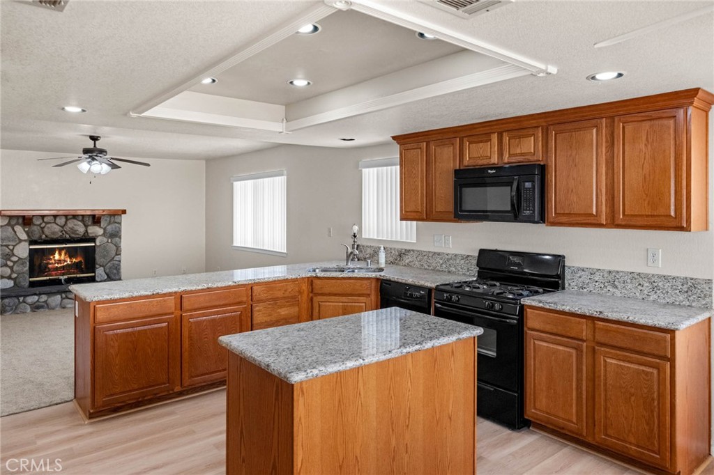 13904 Hidden Valley Road Victorville, CA 92395 - Photo 11 of 47 a kitchen with stainless steel appliances granite countertop a stove top oven a sink dishwasher and a refrigerator with wooden floor