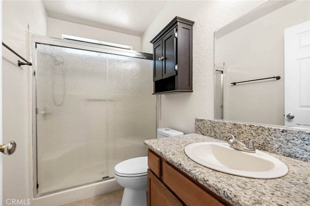 13904 Hidden Valley Road Victorville, CA 92395 - Photo 25 of 47 a bathroom with a granite countertop sink toilet and shower