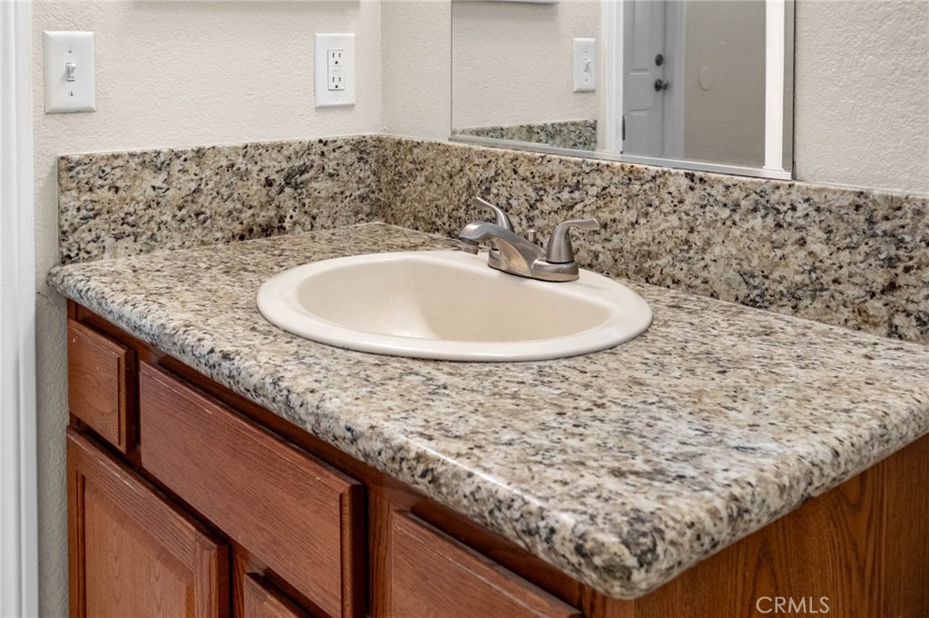 13904 Hidden Valley Road Victorville, CA 92395 - Photo 26 of 47 a bathroom with a granite countertop sink and a mirror