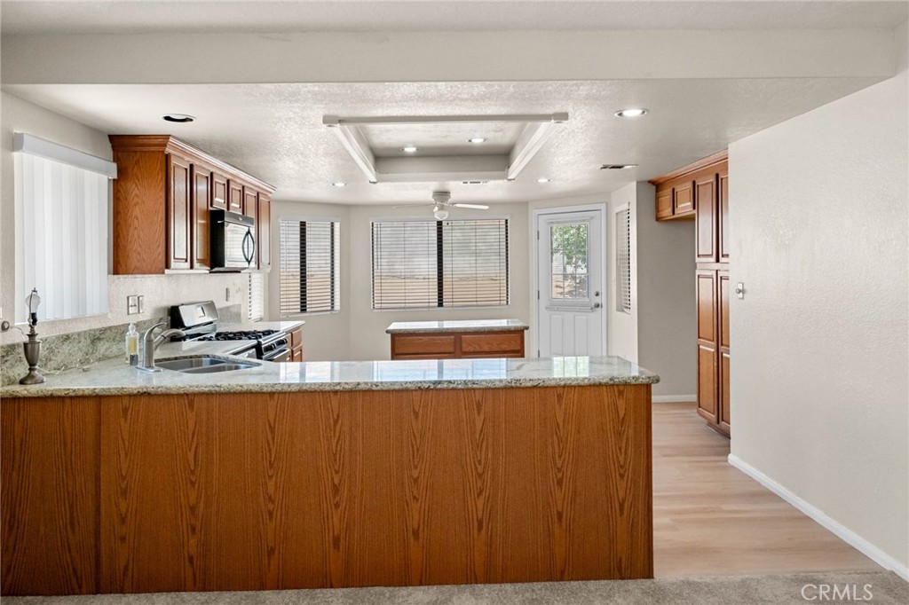13904 Hidden Valley Road Victorville, CA 92395 - Photo 10 of 47 a large kitchen with granite countertop a sink and dishwasher with wooden floor
