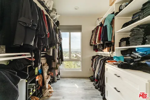 a view of walk in closet with clothes and shoes