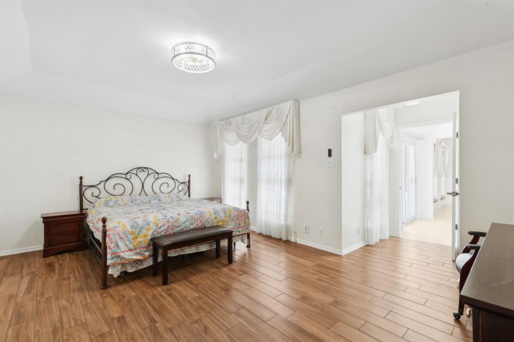 231 Rancho Vista Drive Double Oak, TX 75077 - Photo 13 of 26 a bedroom with a bed and wooden floor