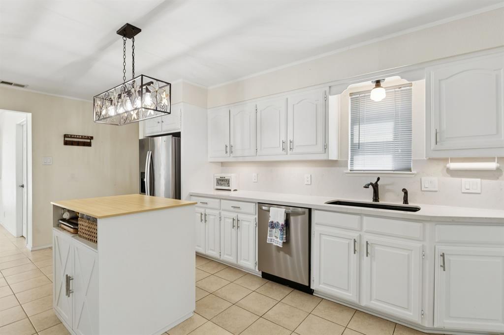 231 Rancho Vista Drive Double Oak, TX 75077 - Photo 8 of 26 a kitchen with white cabinets and chandelier