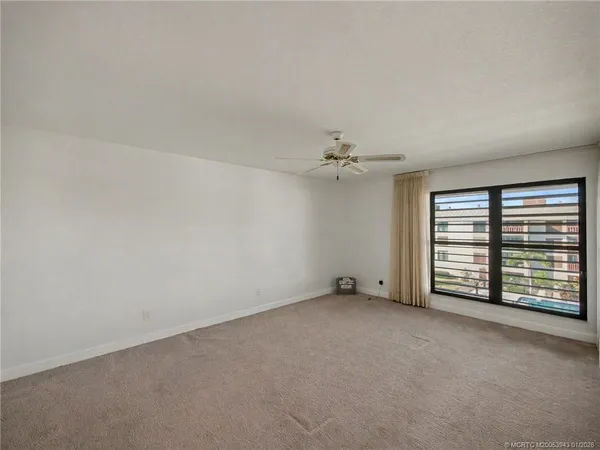 an empty room with windows and fan