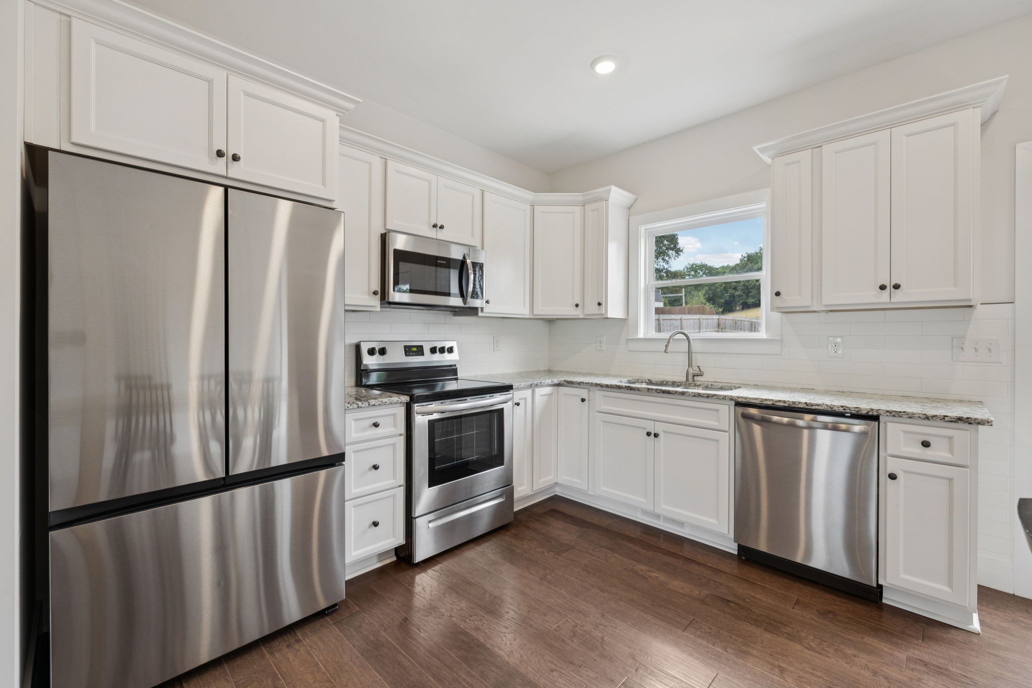 1220 Columbia Road Charlotte, TN 37036 - Photo 8 of 41 a kitchen with white cabinets white stainless steel appliances and wooden floors