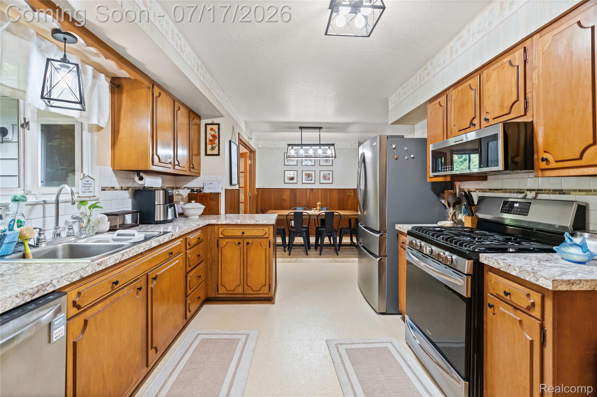 11255 North Center Road Clio, MI 48420 - Photo 14 of 37 Bright kitchen featuring wood-finish cabinetry, light-toned countertops, and stainless steel appliances including a range, microwave, and refrigerator