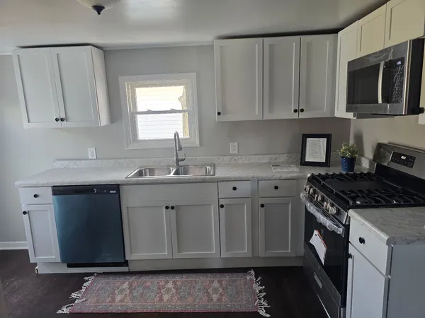 a kitchen with granite countertop white cabinets and stainless steel appliances