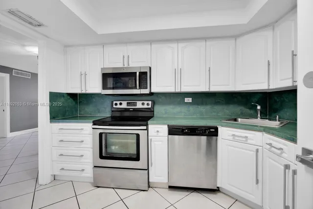 a kitchen with white cabinets and stainless steel appliances