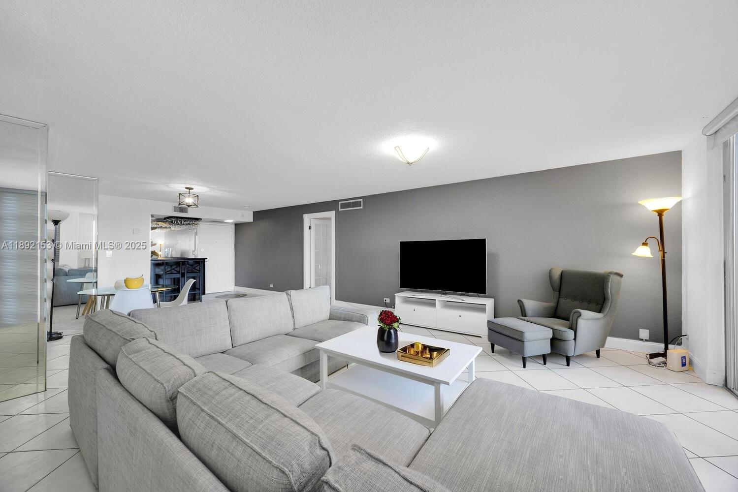 6039 Collins Avenue, Unit 311 Miami Beach, FL 33140 - Photo 3 of 26 a living room with furniture and a flat screen tv