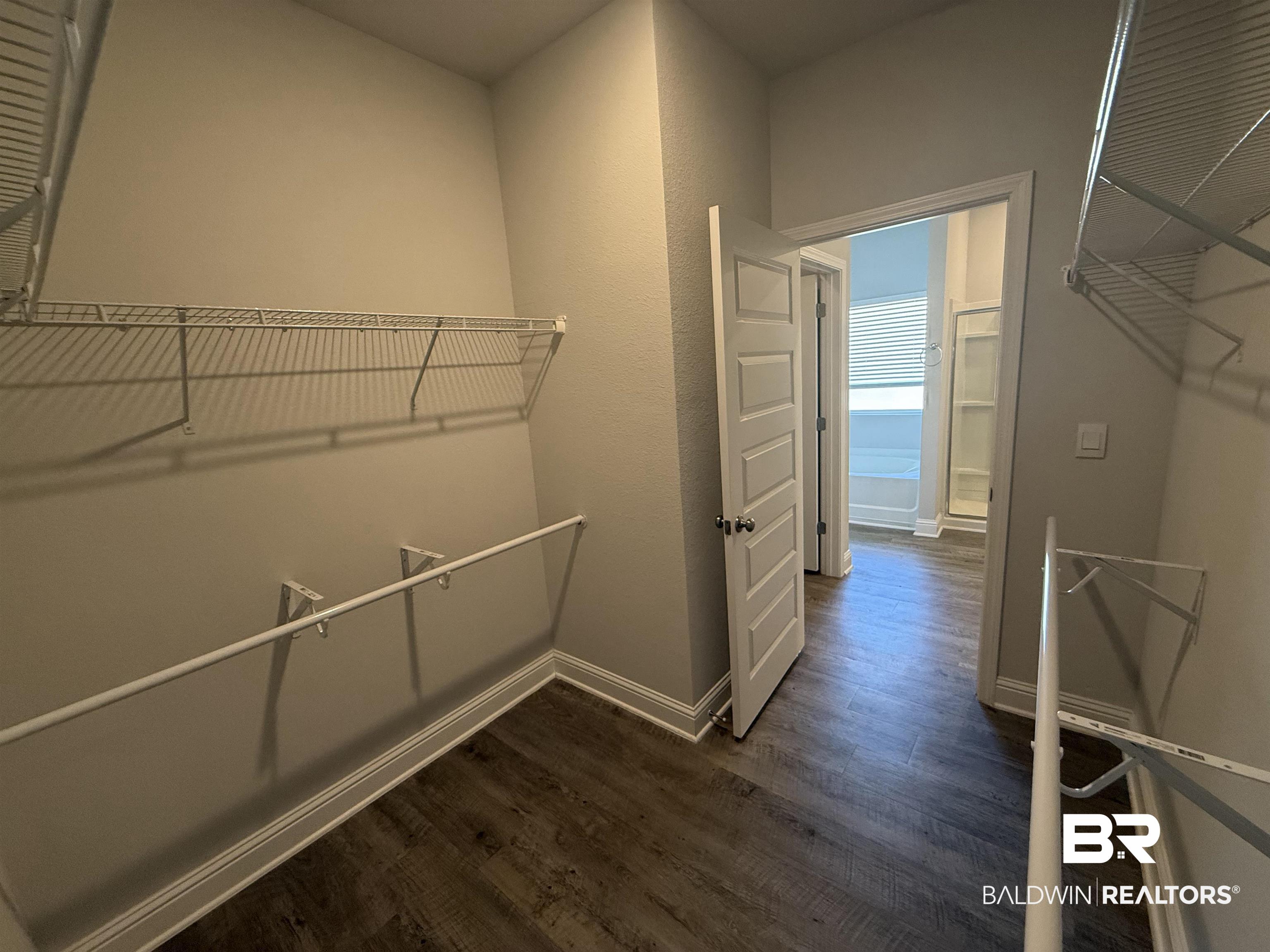 23247 Lieutenant Avenue Foley, AL 36535 - Photo 35 of 47 Walk-in closet with wire shelving and hanging rods, wood-finish flooring, and five-panel interior door