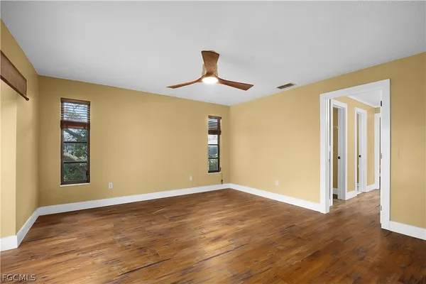 a view of empty room with wooden floor and fan