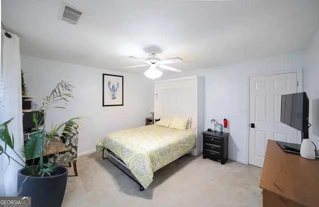 a bedroom with a bed potted plant on dresser and a chandelier