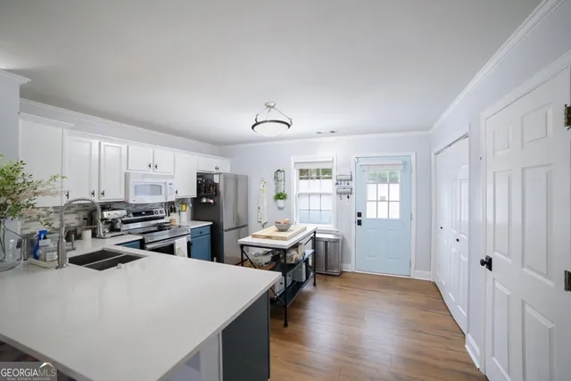 a kitchen that has a lot of cabinets a sink and appliances