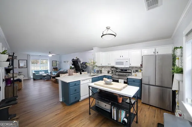 a kitchen with a refrigerator a stove and a dining table with wooden floor